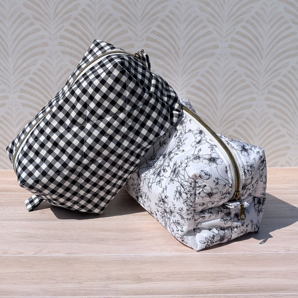Two bags, one checkered and one with floral pattern, on a wooden surface with a light background.