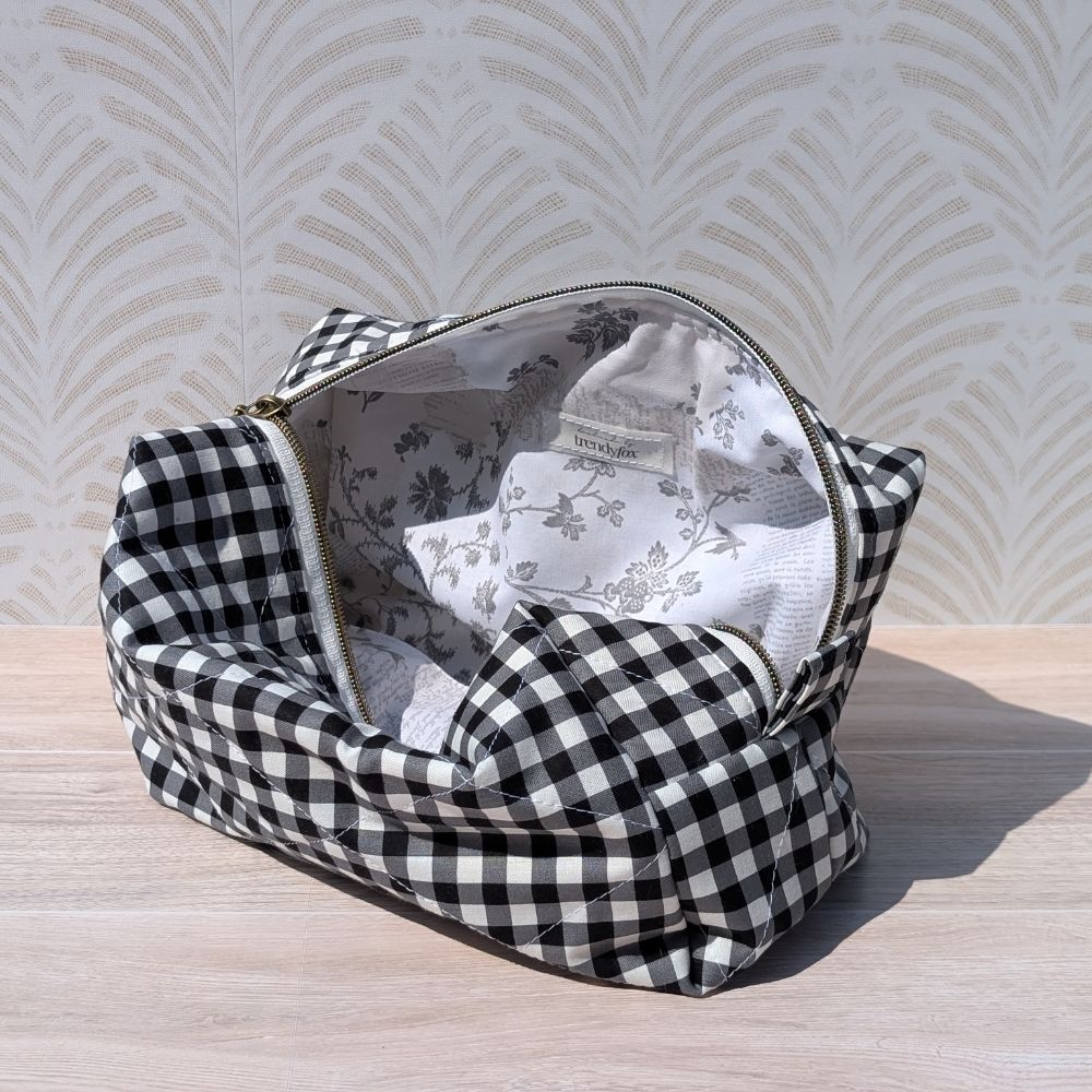 Black and white checkered bag with floral interior on a light wooden surface.