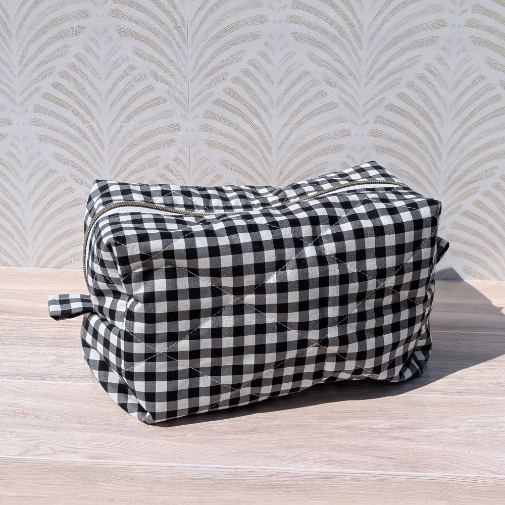 Black and white checkered bag on a wooden surface with a patterned wall in the background