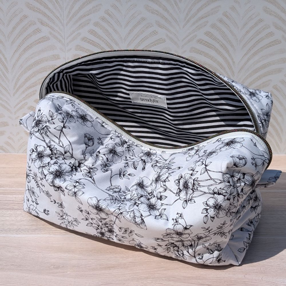 Floral-patterned makeup bag with striped lining on a wooden surface
