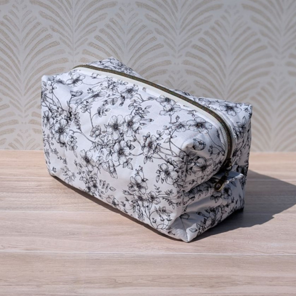 Floral-patterned toiletry bag on a wooden surface with a textured wall background