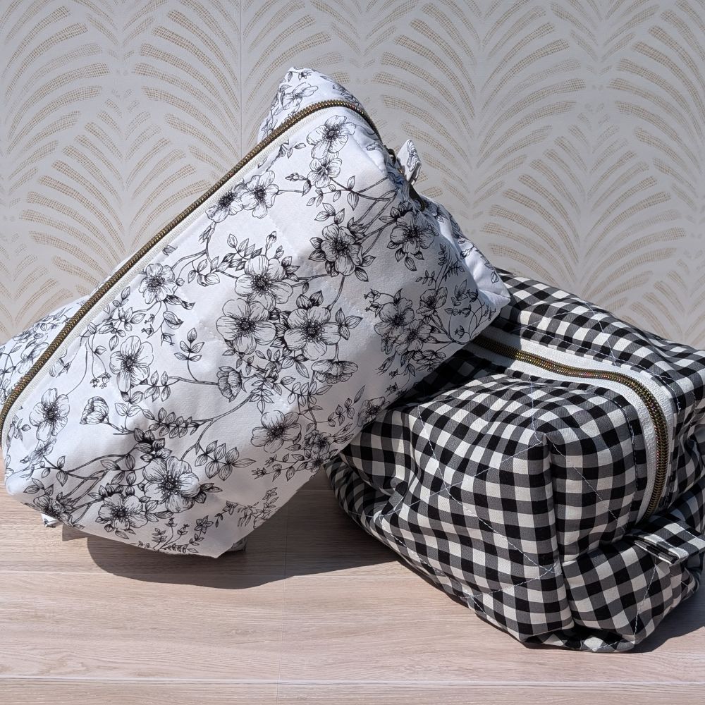 Floral-patterned pouch and checkered pouch on a wooden surface with a patterned wall background