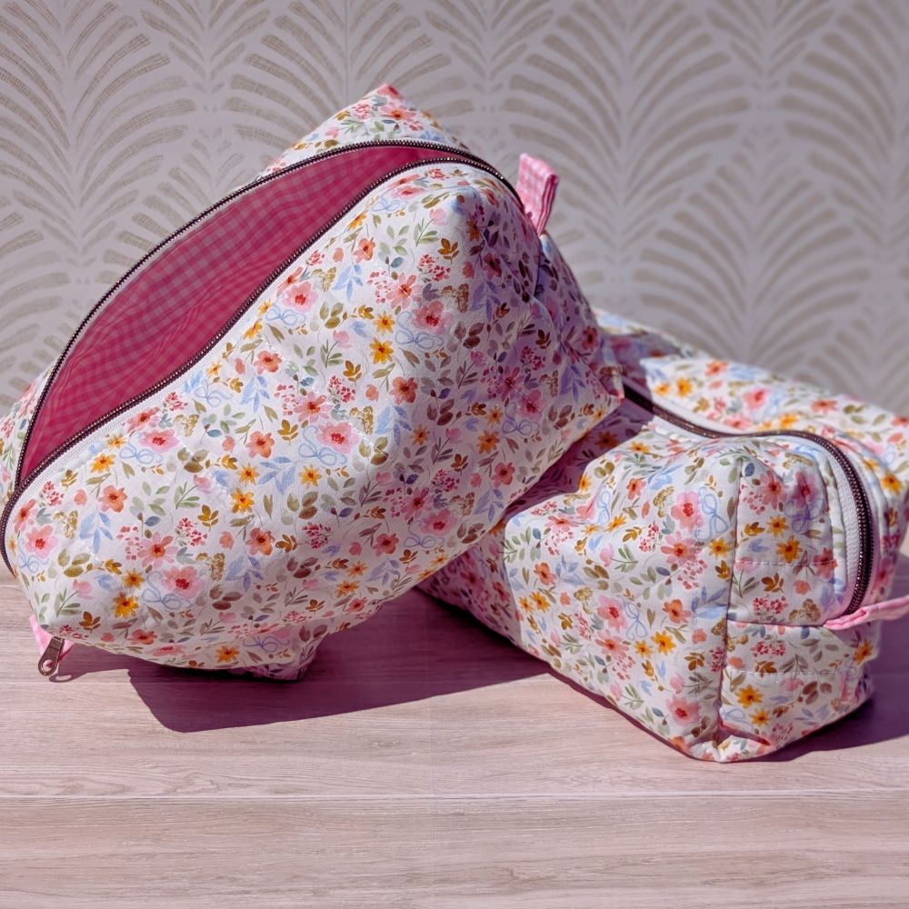 Two floral-patterned bags on a wooden surface with a patterned wall background