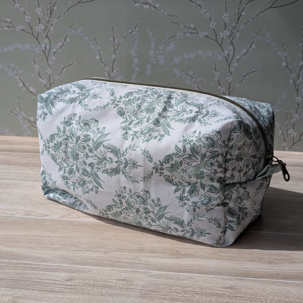 Floral-patterned toiletry bag on a wooden surface with a neutral background