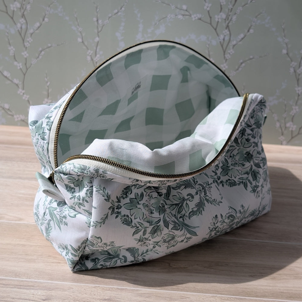 Floral-patterned makeup bag with a checkered lining on a wooden surface.