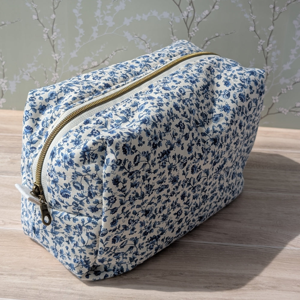 Floral-patterned toiletry bag on a wooden surface with a light gray background