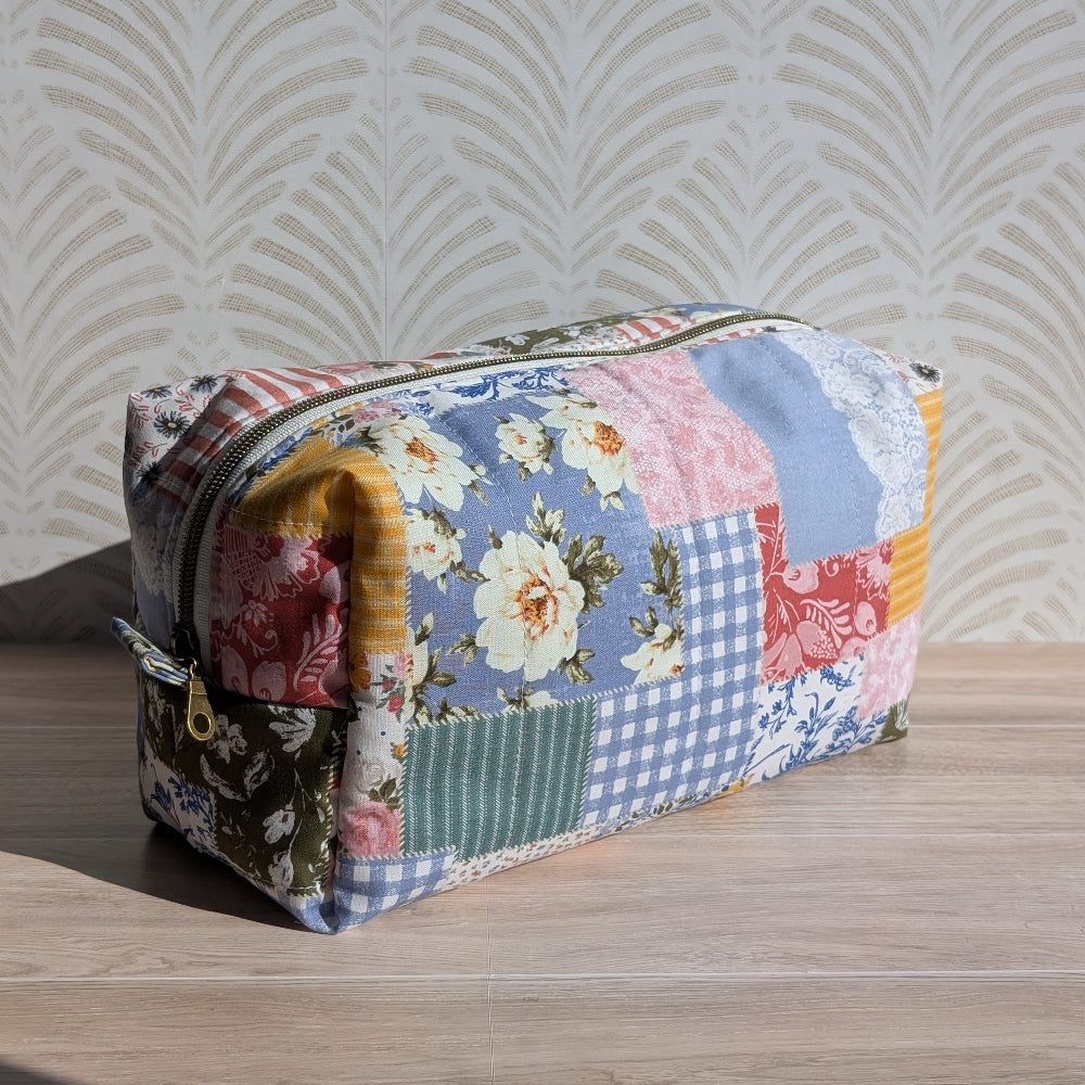 Patchwork-style cosmetic bag on a wooden surface with a patterned wall in the background