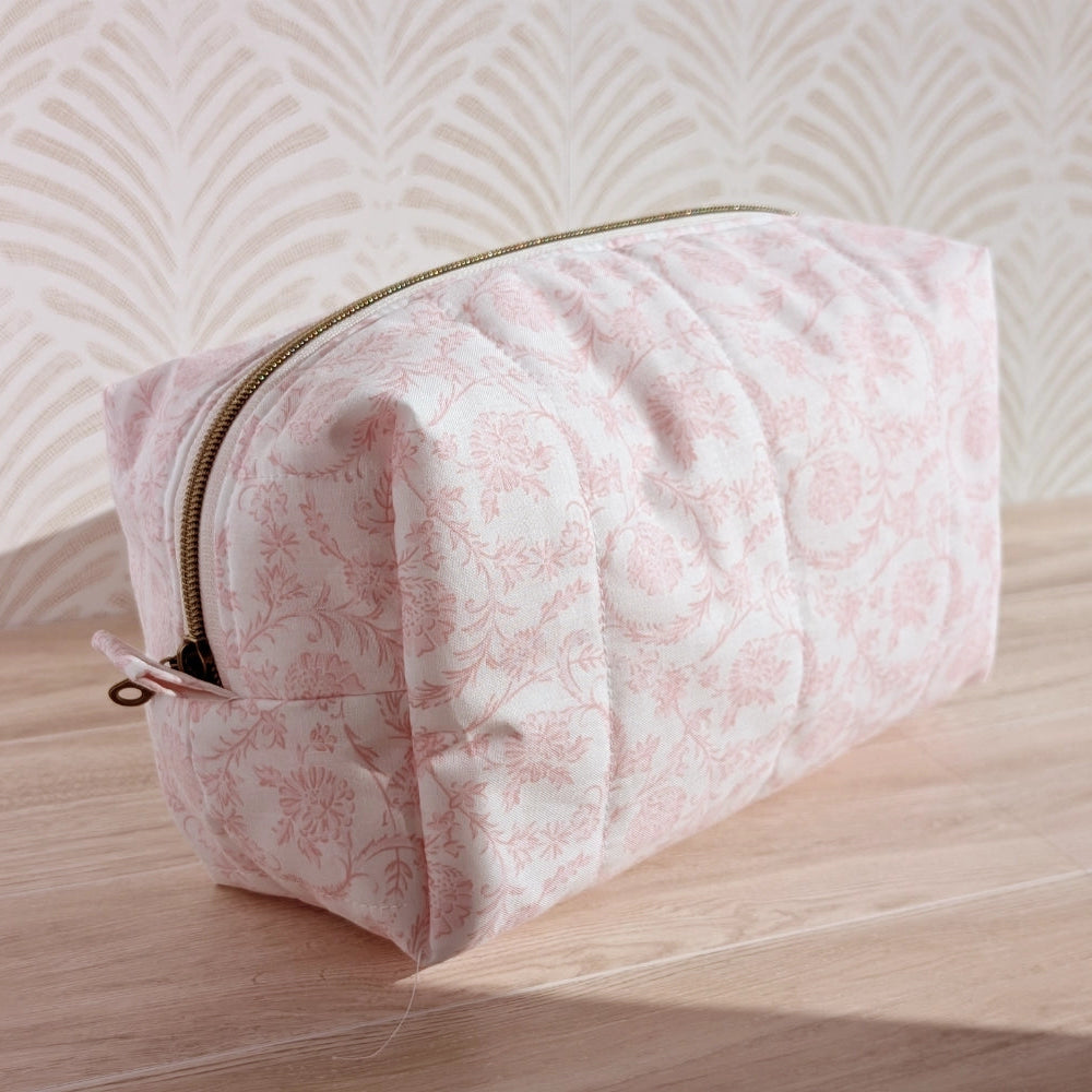 Pink floral pouch on a wooden surface with a light background