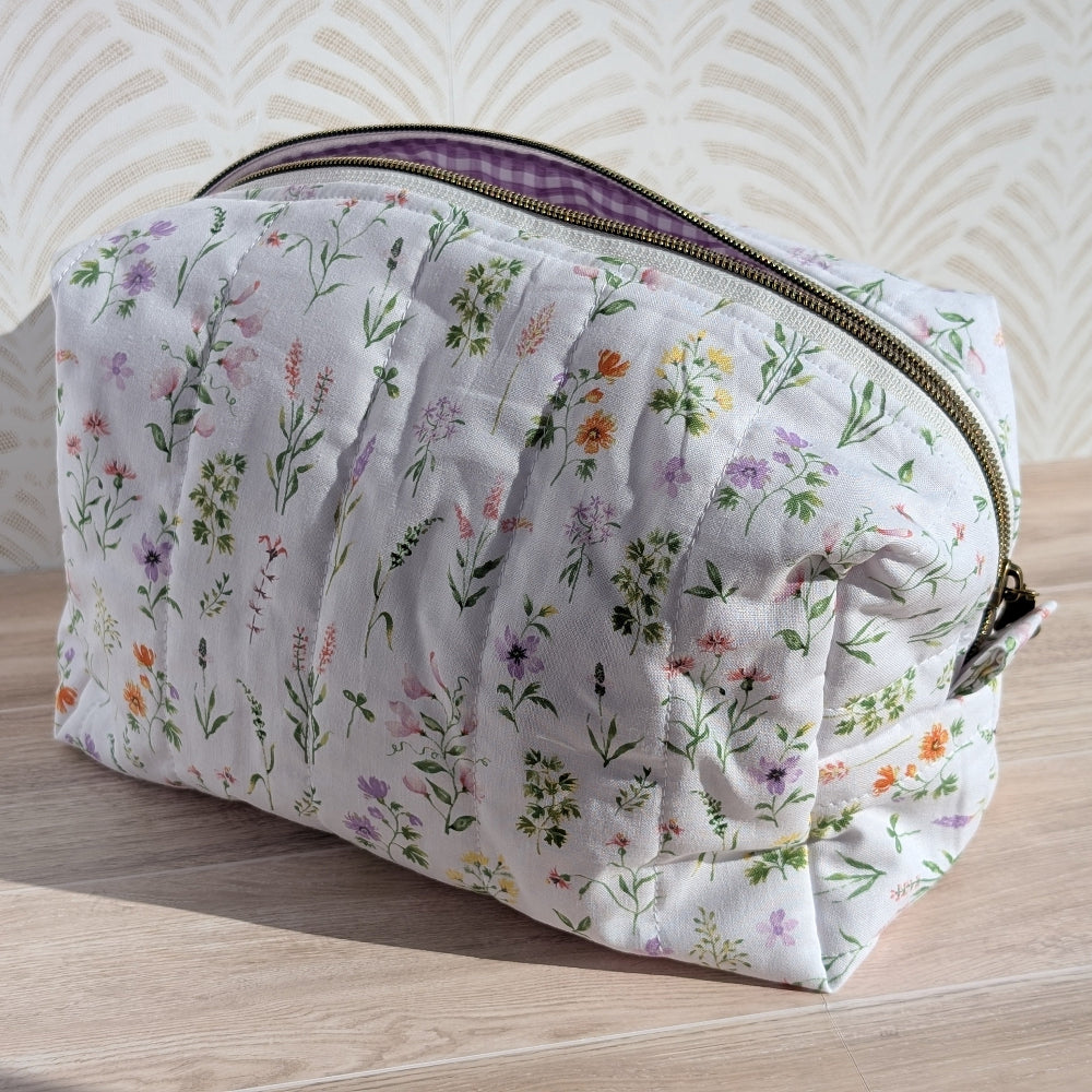 Floral-patterned makeup bag on a wooden surface with a wavy beige background