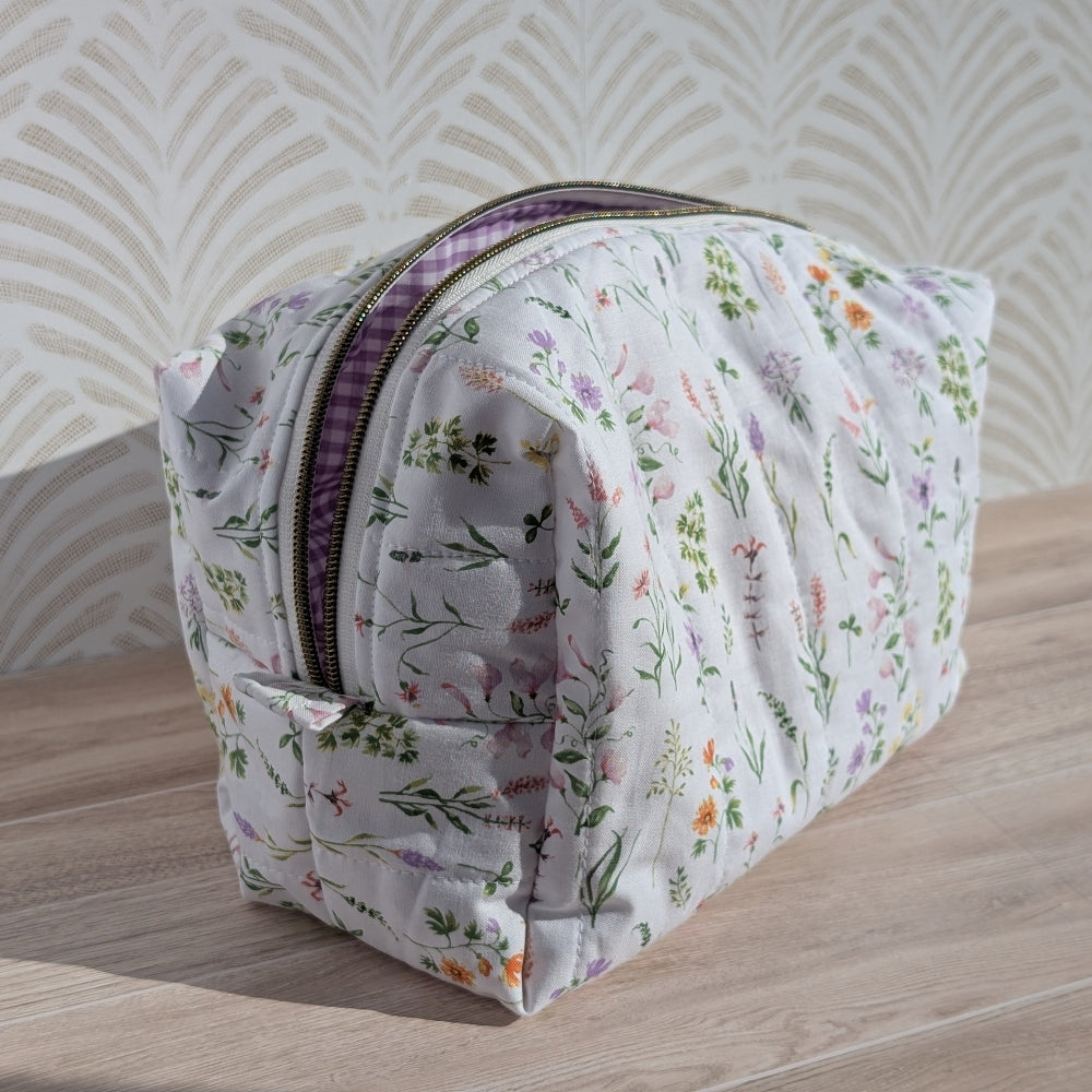 Floral-patterned makeup bag on a wooden surface with a wavy beige background