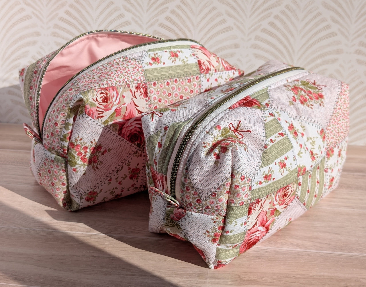 Floral-patterned makeup bags on a wooden surface with a textured wall background