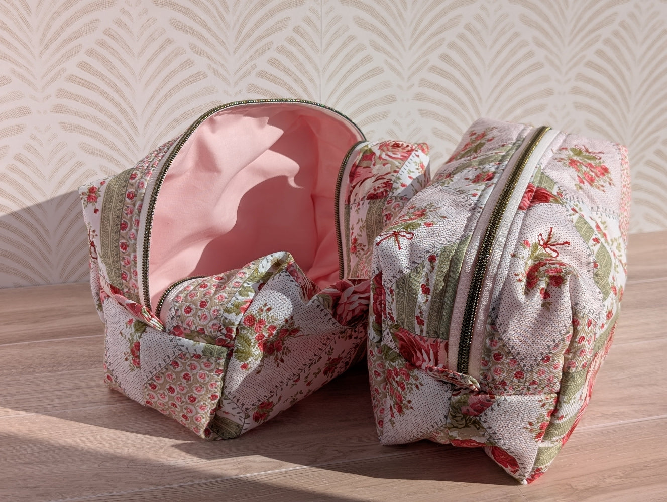Two floral-patterned makeup bags on a wooden surface with a light background