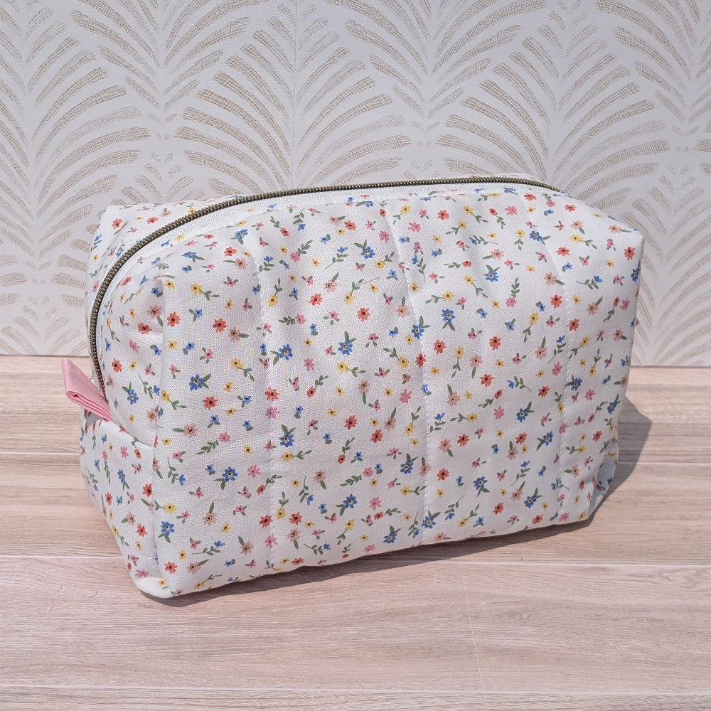 Floral-patterned pouch on a wooden surface with a decorative wall background