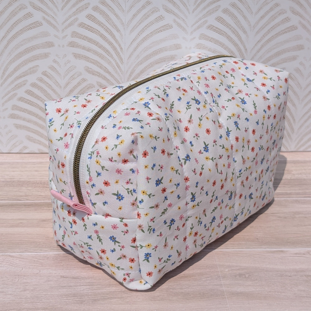 Floral-patterned toiletry bag on a wooden surface with a textured wall background