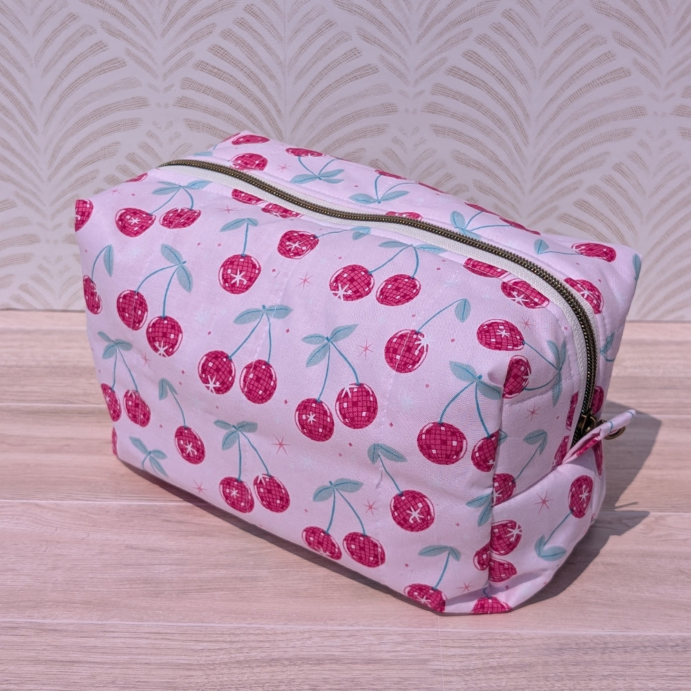 Cosmetic bag with cherry pattern on a wooden surface