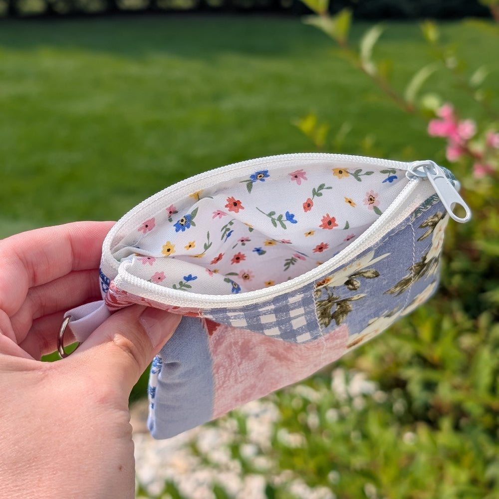 Hand holding a small fabric pouch with floral pattern against a natural background