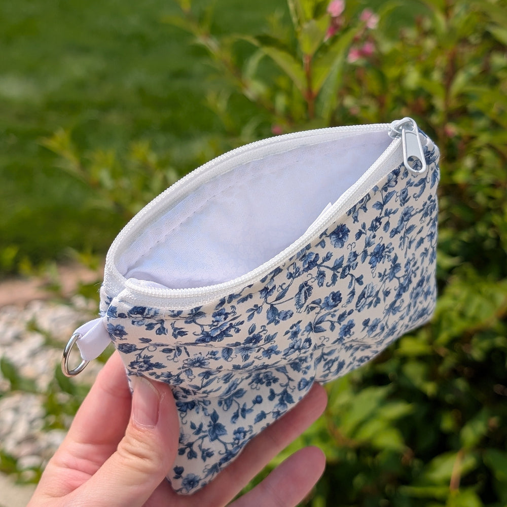 Floral-patterned pouch held in front of a green outdoor background