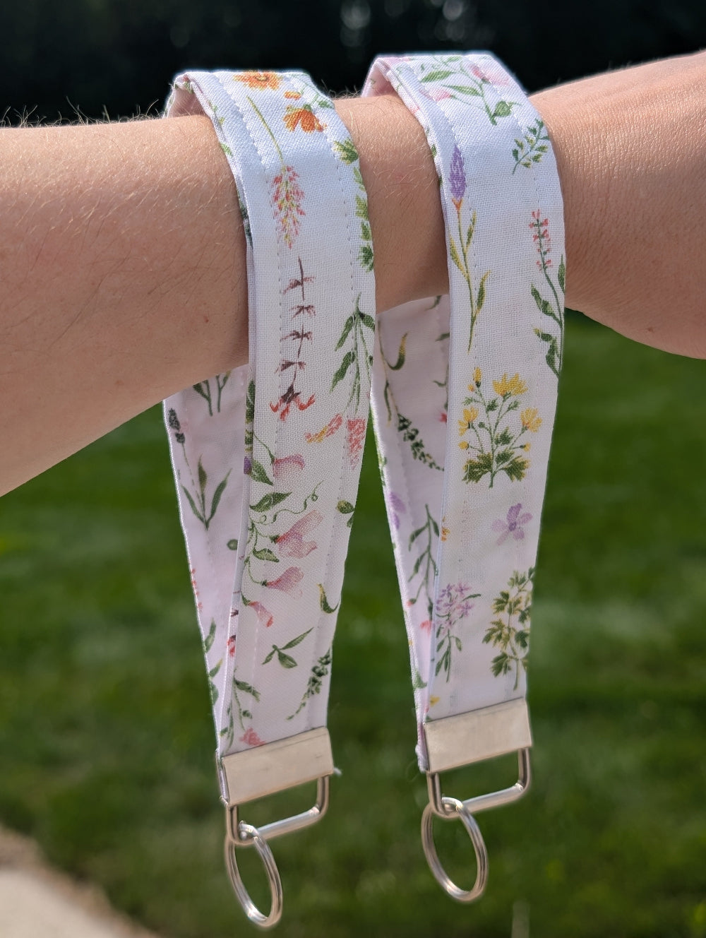 Two floral-patterned straps on a person's wrist with a blurred green background