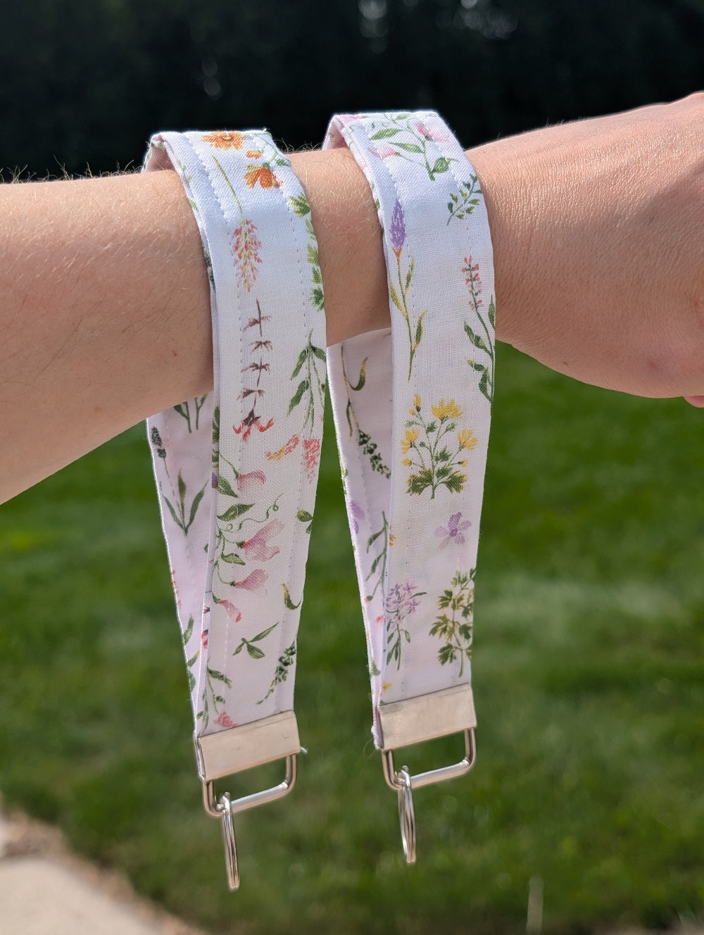 Two floral-patterned straps on a person's wrist with a blurred green background