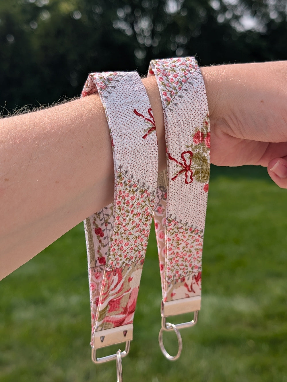 Floral patterned strap worn on a wrist with a blurred green background