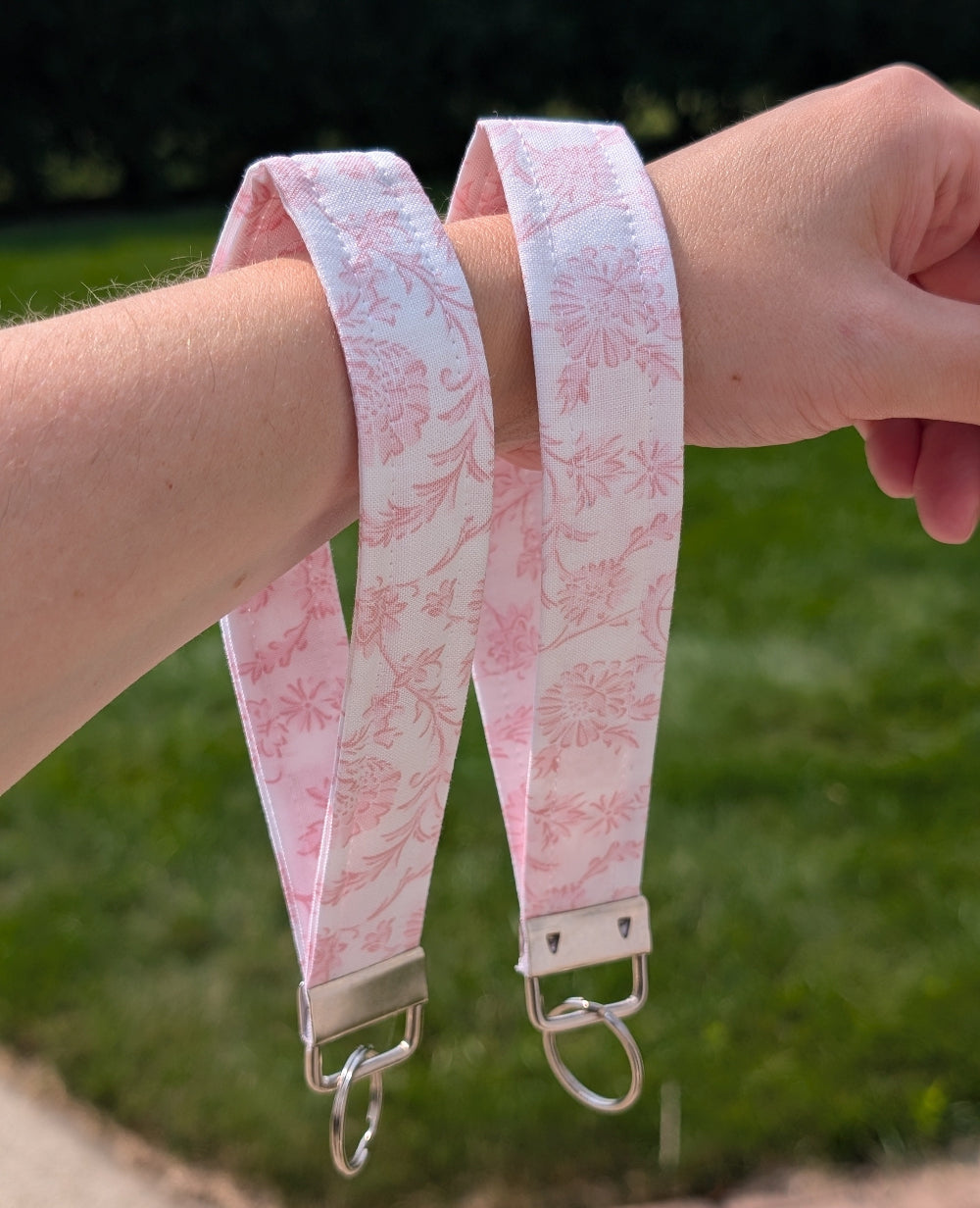 Pink floral patterned strap held by a person with a blurred green outdoor background