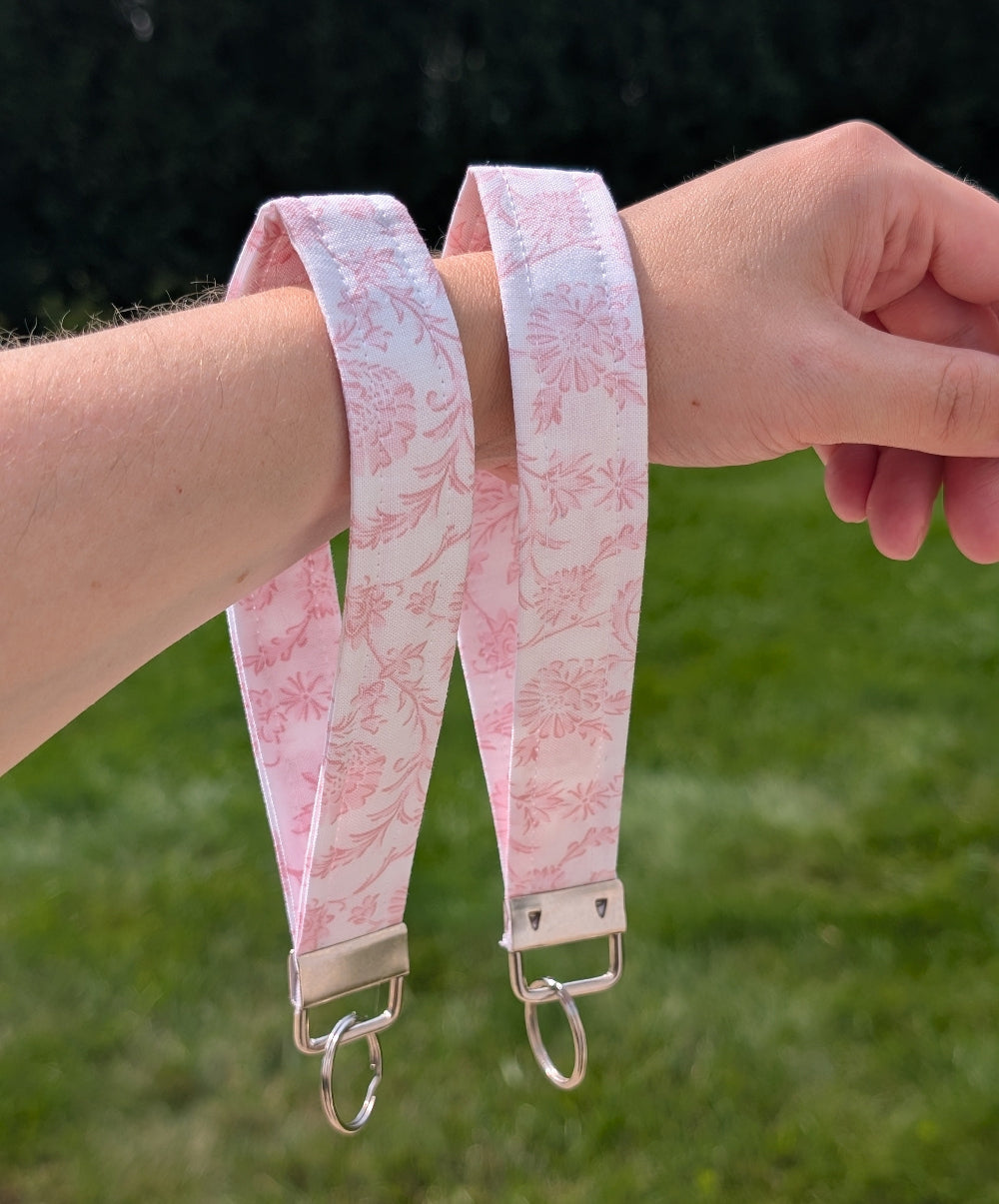 Pink floral strap with metal hooks on a blurred green background