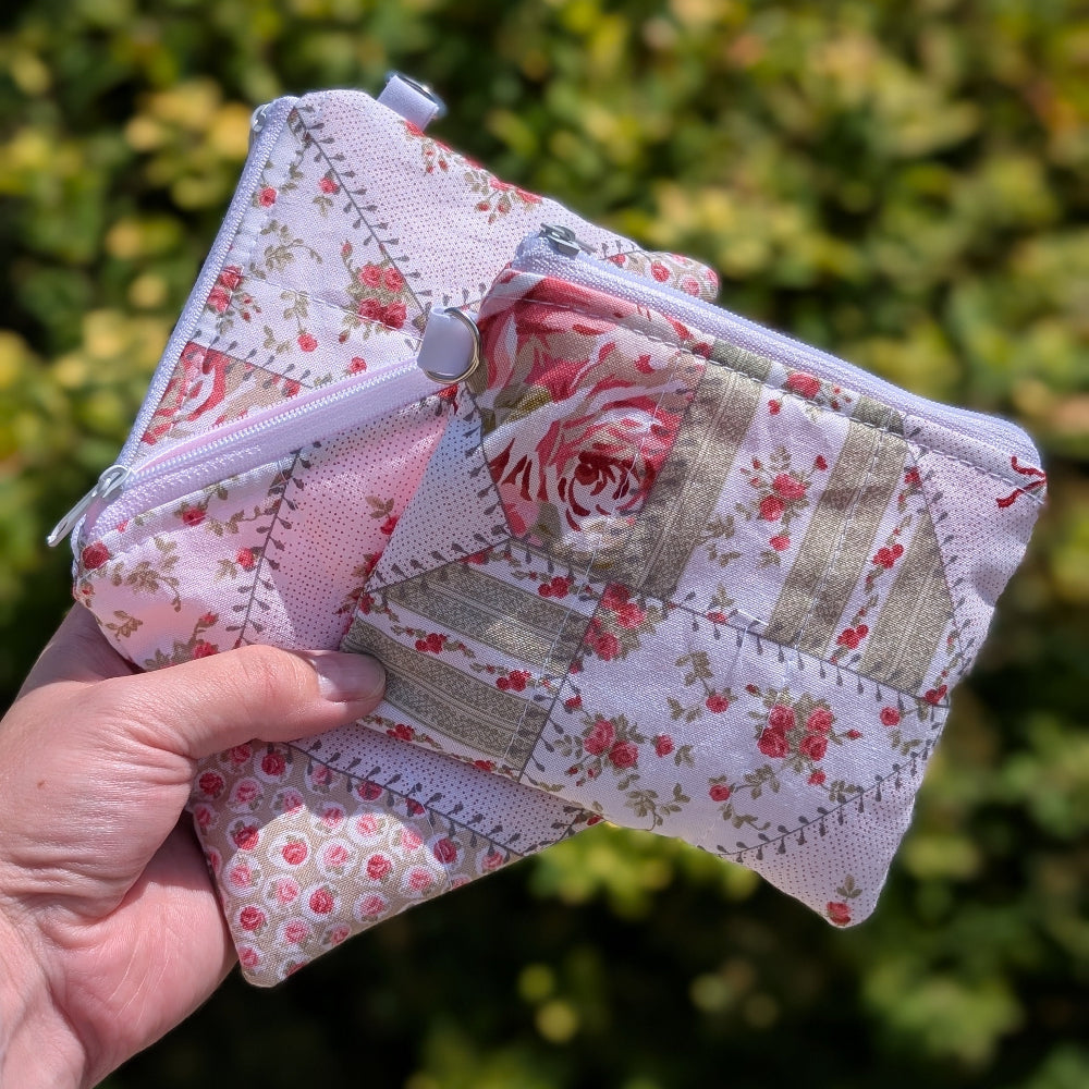Hand holding a floral and patchwork patterned pouch against a green leafy background
