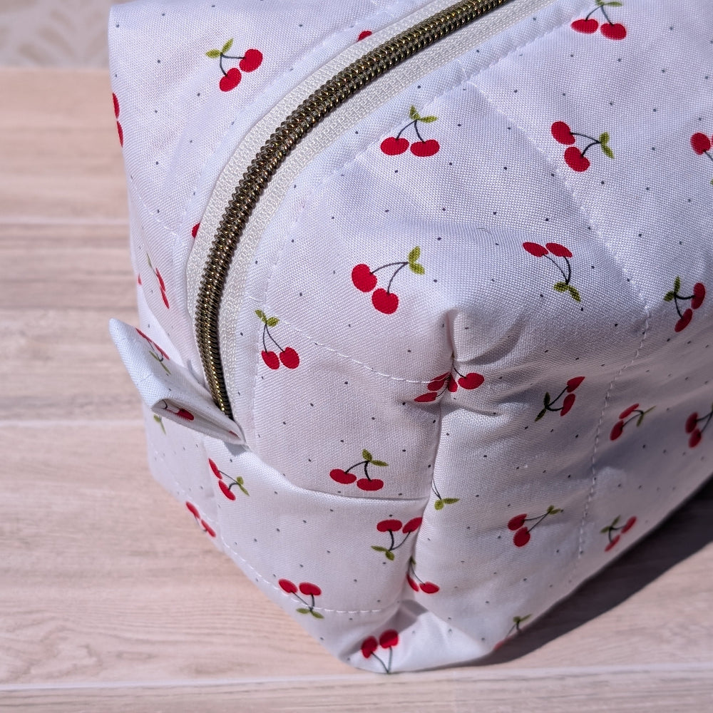 White pouch with cherry pattern on a wooden surface