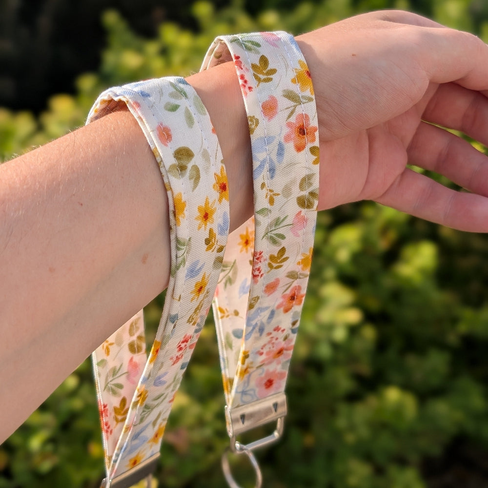 Floral patterned lanyard being worn on a wrist with a blurred green background