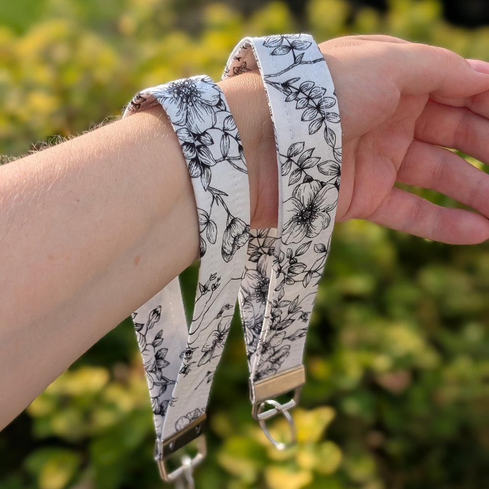 Floral-patterned strap worn on a wrist with a blurred green background