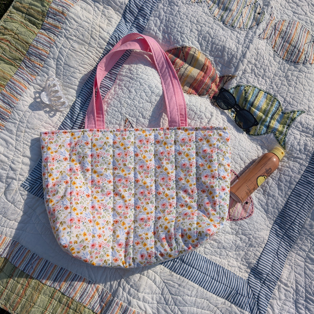 Floral-patterned tote bag on a quilt with colorful fish designs