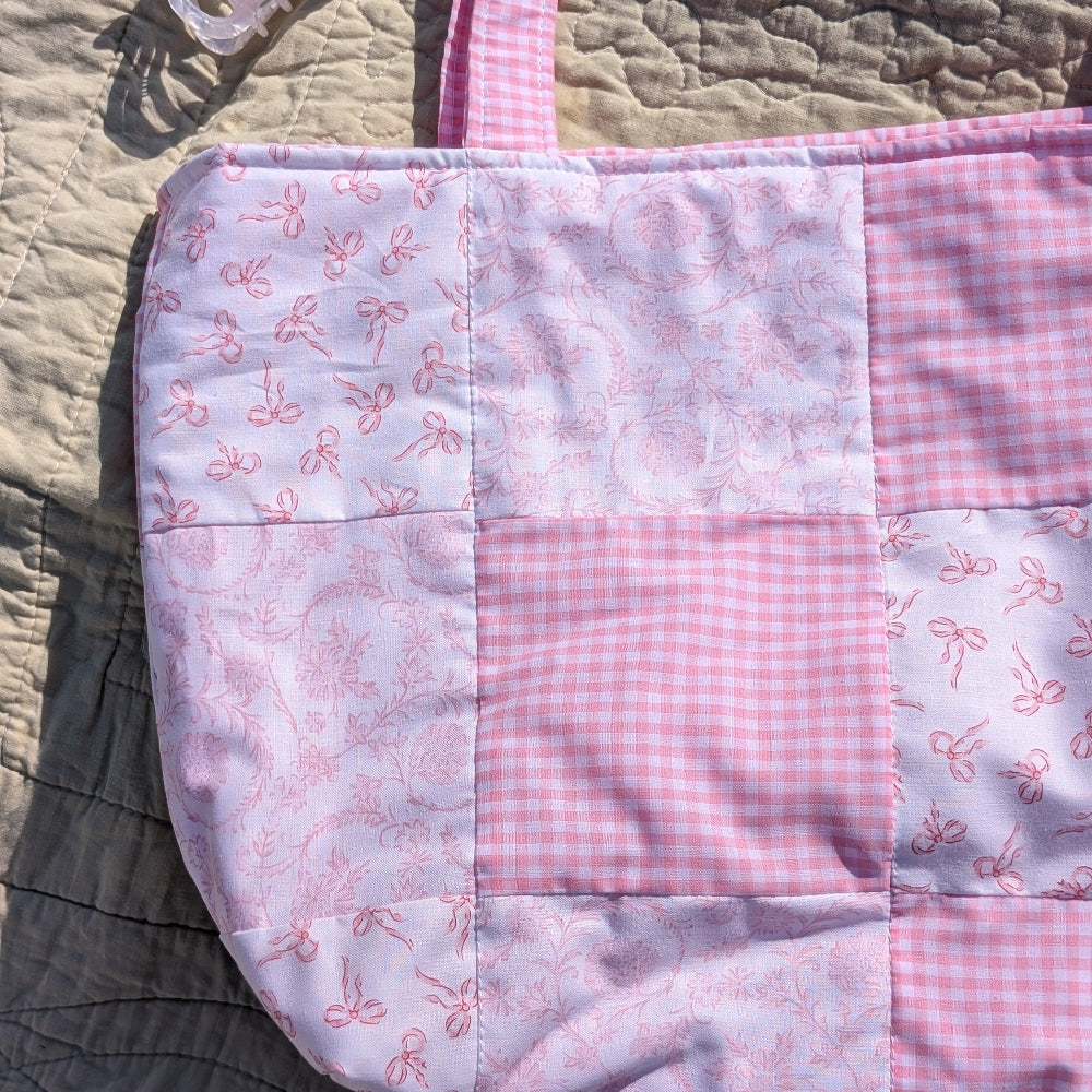 Patchwork quilt with pink and white patterns on a textured surface