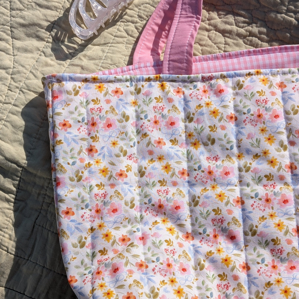 Floral-patterned bag with pink handle on a textured surface